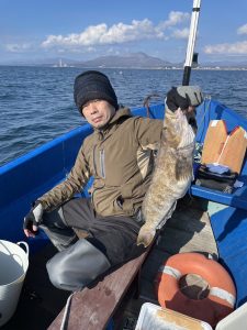 船上でアブラコを釣りあげた笑顔の男性