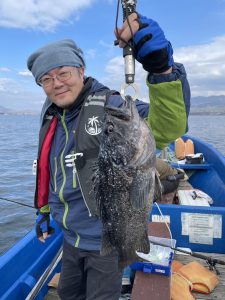 船上でソイを釣りあげた笑顔の男性