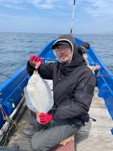 船上でクロガシラカレイを釣りあげた笑顔の男性