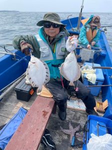 船上でマガレイを釣りあげた笑顔の男性