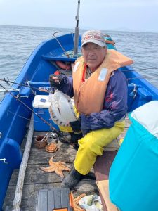 船上でクロガシラカレイを釣りあげた笑顔の男性