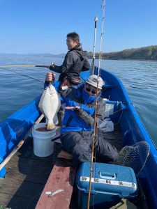 船上でヒラメを釣りあげた笑顔の男性