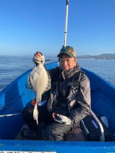 船上でクロガシラカレイを釣りあげた笑顔の男性