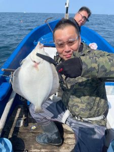 船上でマガレイを釣りあげた笑顔の男性