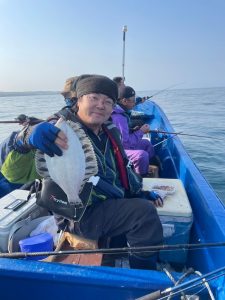 船上でクロガシラカレイを釣りあげた笑顔の男性