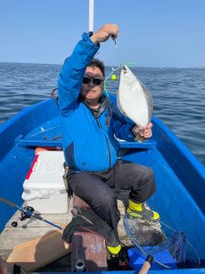 船上でヒラメを釣りあげた笑顔の男性