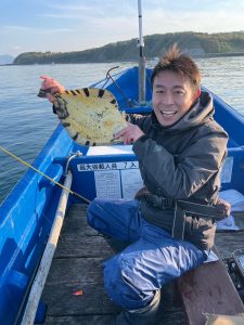 船上でマツカワガレイを釣りあげた笑顔の男性