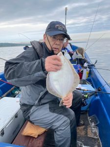 船上でマガレイを釣りあげた笑顔の男性