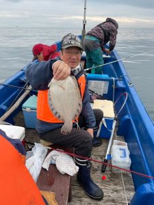 船上でクロガシラカレイを釣りあげた笑顔の男性