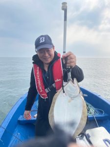 船上でヒラメを釣りあげた笑顔の男性