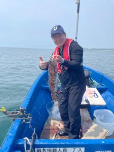 船上でアブラコを釣りあげた笑顔の男性