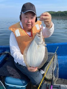 船上でヒラメを釣りあげた笑顔の男性