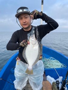 船上でヒラメを釣りあげた笑顔の男性