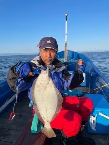 船上でヒラメを釣りあげた笑顔の男性