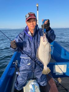 船上でヒラメを釣りあげた笑顔の男性