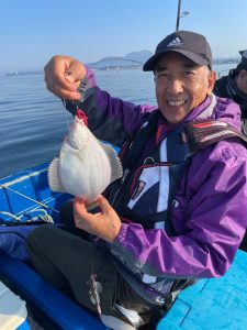 船上でマガレイを釣りあげた笑顔の男性