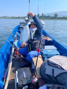 船上でヒラメを釣りあげた笑顔の男性