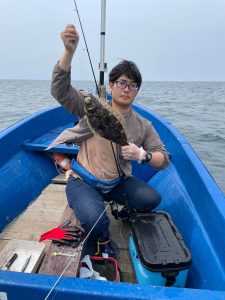 船上でヒラメを釣りあげた笑顔の男性