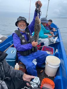 船上でアブラコを釣りあげた笑顔の男性