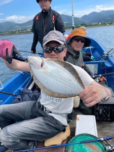 船上でヒラメを釣りあげた笑顔の男性