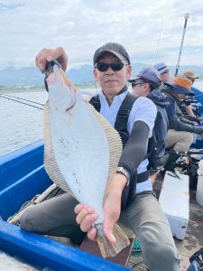 船上でヒラメを釣りあげた笑顔の男性