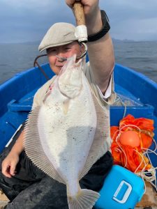 船上でマガレイを釣りあげた笑顔の男性