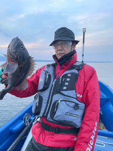 船上でクロゾイを釣りあげた笑顔の男性