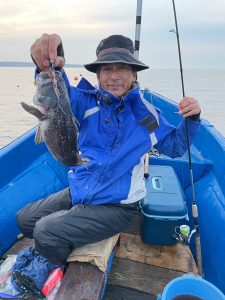 船上でクロゾイを釣りあげた笑顔の男性