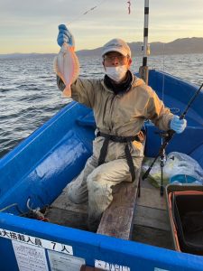 船上でマガレイを釣りあげた笑顔の男性