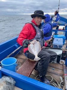 船上でマガレイを釣りあげた笑顔の男性