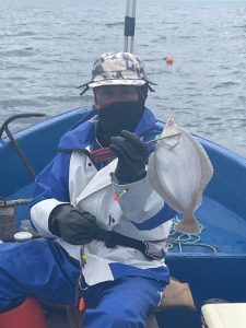 船上でマガレイを釣りあげた笑顔の男性