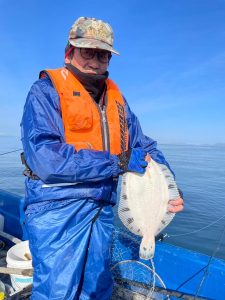 船上でクロガシラを釣りあげた笑顔の男性