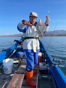 船上でマガレイを釣りあげた笑顔の男性