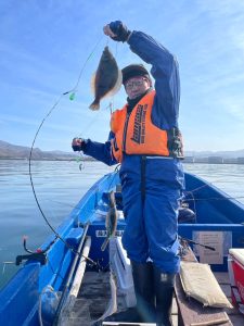 船上でマガレイを釣りあげた笑顔の男性